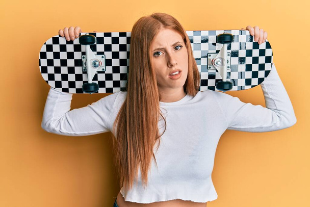 Jeune femme irlandaise tenant skate expression désemparée et confuse. concept de doute.  - Photo, image
