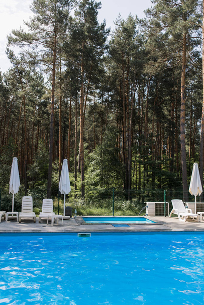 a swimming pool in the forest with umbrellas in summer - Foto, imagen