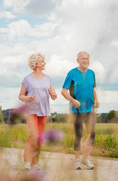 Fit and active senior couple running outdoors as exercise - Photo, Image