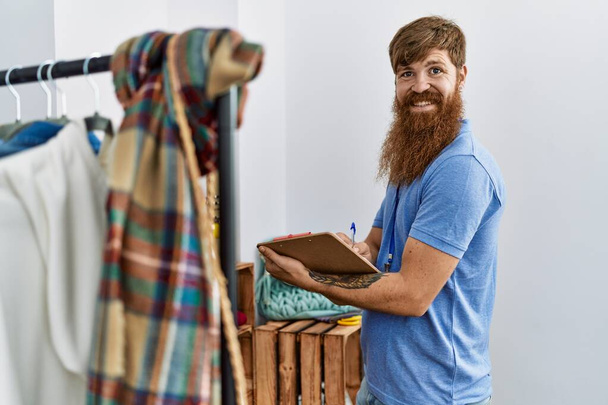 Junger irischer Ladenbesitzer lächelt glücklich bei der Arbeit im Bekleidungsgeschäft. - Foto, Bild