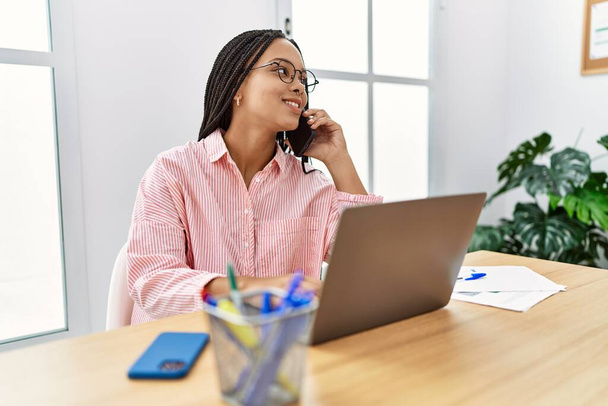 Молодая американка из Африки разговаривает на смартфоне, работая в офисе - Фото, изображение