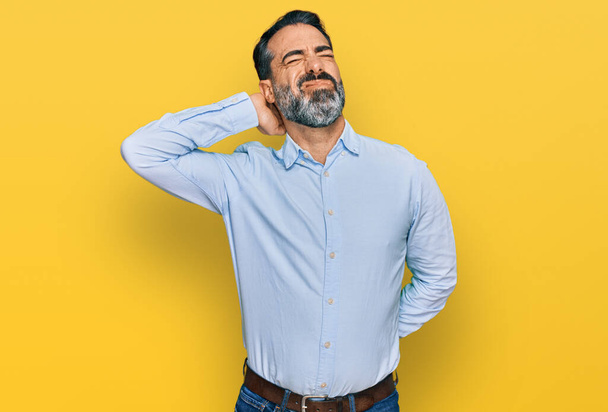 Чоловік середнього віку з бородою в діловій сорочці страждає від болю в шиї, торкається шиї рукою, м'язовий біль
  - Фото, зображення