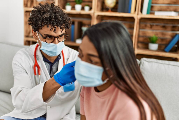Giovane medico latino uomo auscultare l'orecchio della donna utilizzando otoscopio in sala d'esame. - Foto, immagini