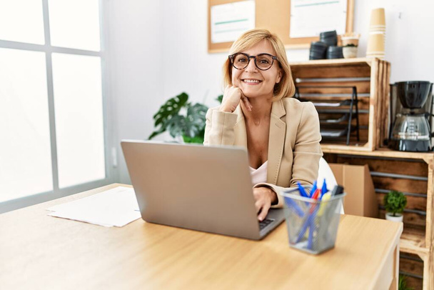 Mulher loira de meia idade sorrindo confiante trabalhando no escritório - Foto, Imagem