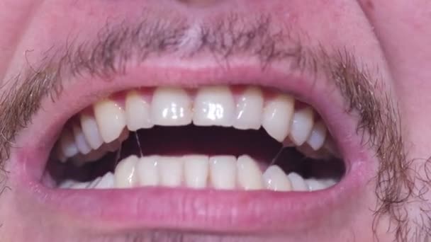 Молодой человек со здоровыми зубами показывает прямые зубы щелкает ими. Закрыть - Кадры, видео