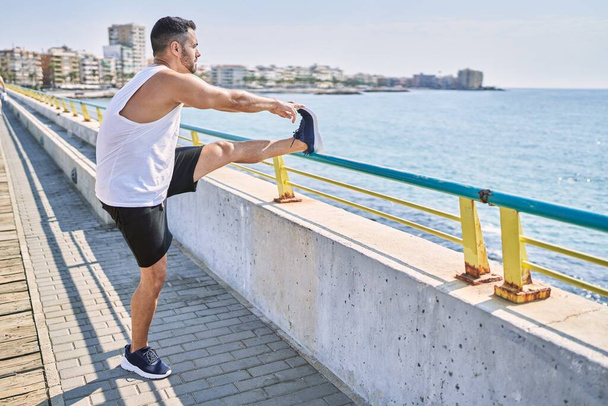 Latinomies venyttely jalat treenauksen jälkeen ulkona aurinkoisena päivänä - Valokuva, kuva