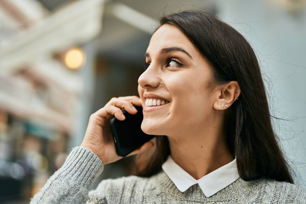 Genç İspanyol kadın gülümsüyor. Şehirdeki akıllı telefondan konuşuyor.. - Fotoğraf, Görsel