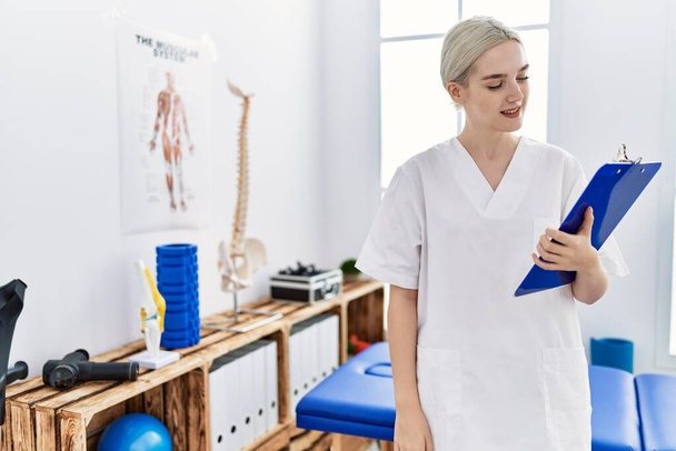 Молодая белая женщина в форме физиотерапевта работает в клинике - Фото, изображение