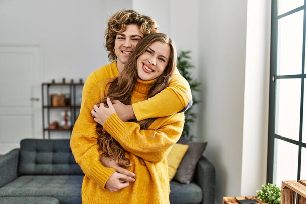 Молода біла пара посміхається впевнено обіймає один одного вдома
 - Фото, зображення