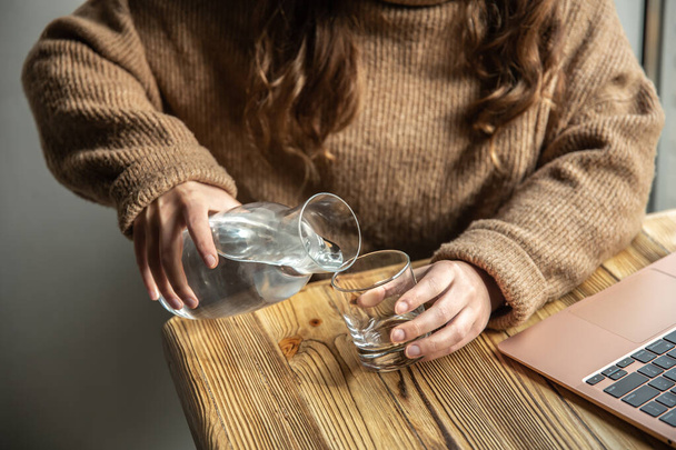 Nainen kaataa vettä lasiin dekantterista.. - Valokuva, kuva