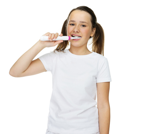 Tyttö harjaa hampaitaan sähköharjalla
 - Valokuva, kuva