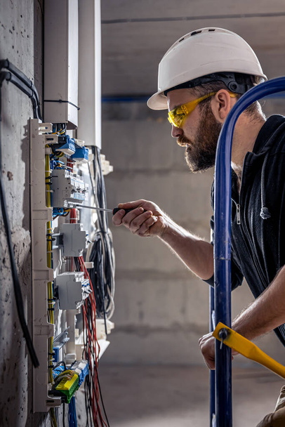 un électricien masculin travaille dans un standard avec un câble de connexion électrique
. - Photo, image