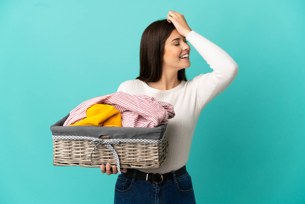 Teenager Brazilian girl holding a clothes basket isolated on blue background has realized something and intending the solution - Fotografie, Obrázek