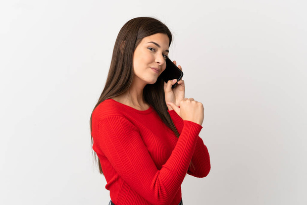 Teenager Brazilian girl using mobile phone over isolated white background proud and self-satisfied - Foto, afbeelding