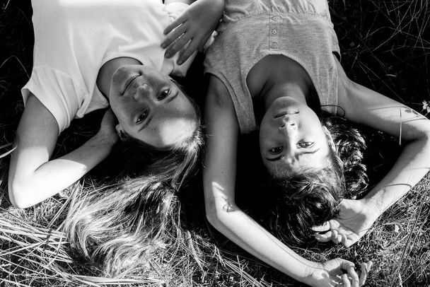 Dos adolescentes tumbadas en el césped en el parque de verano. Foto en blanco y negro. - Foto, imagen