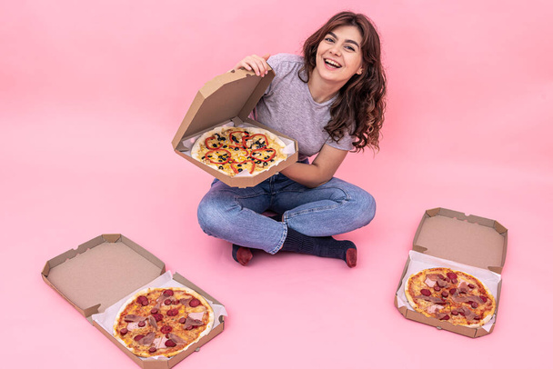 Fille attrayante avec pizza de boîtes pour la livraison sur un fond rose. - Photo, image