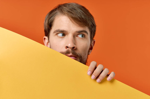 emotivní muž drží žlutý banner design oranžové pozadí - Fotografie, Obrázek