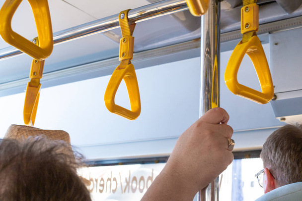 woman holds grab rails on the bus while driving - Valokuva, kuva