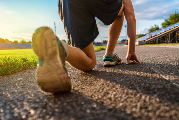 низький старт для бігу, вид на ногу, хлопчик-підліток біжить по трасі стадіону, футбольне поле з зеленою травою концепція спорту та здоров'я
 - Фото, зображення