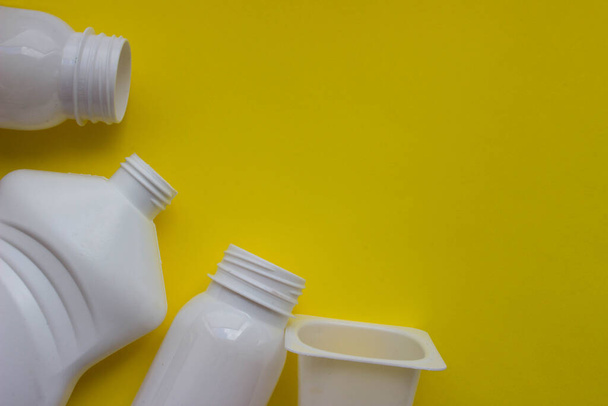 White plastic bottles on yellow background with place for your design. Top view - 写真・画像