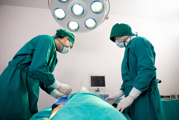 病院の手術室で患者の緊急時に酸素マスクを保持チーム医師とアシスタント,外科医の治癒と手術,呼吸の問題,楽器医療と健康. - 写真・画像
