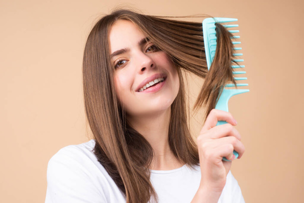 Portrait of charming brunette hair lady combing hair with hairbrush comb, isolated. - Photo, image