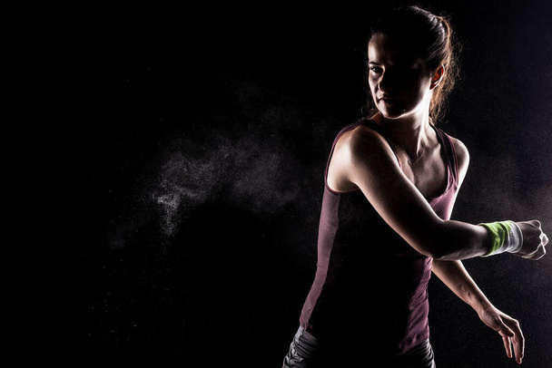 Kickboxer kirl with magnesium powder on her hands, punching with dust visible. - Fotoğraf, Görsel