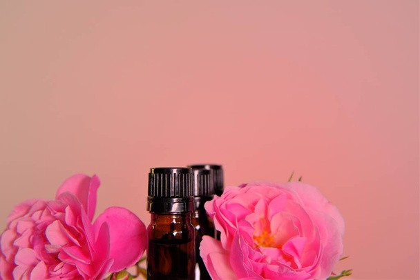 エッセンシャルオイルをバラ。アロマセラピーと化粧品のコンセプト。ピンクを基調としたグラスボトルセットとピンクのバラの花有機天然バラ油有機バイオ化粧品 - 写真・画像