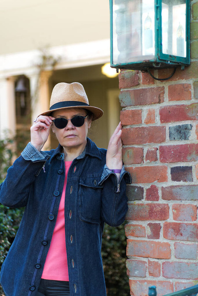 beautiful woman strolls down the street wearing glasses, hat and a jacket - Foto, Imagen
