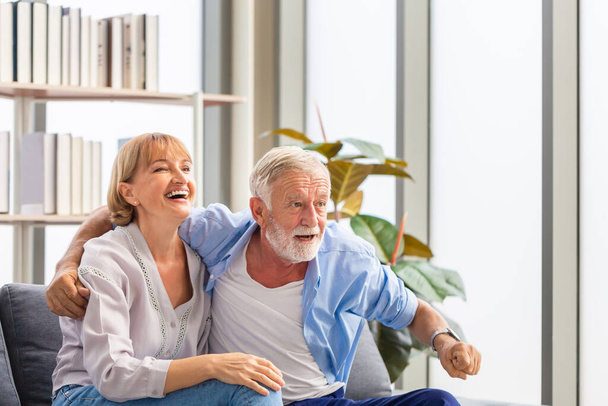 Portret szczęśliwej pary seniorów dopingować ich ulubionej drużyny podczas oglądania meczu piłki nożnej w salonie, Starsza kobieta i mężczyzna relaks na przytulnej kanapie w domu, Happy koncepcji rodziny - Zdjęcie, obraz