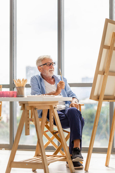 Oudere man schilderen op een doek, Lachende volwassen man schilderen op doek thuis, Gelukkige pensionering concepten - Foto, afbeelding