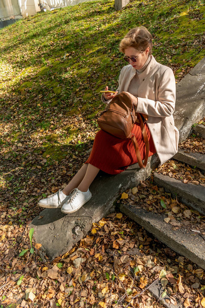 Mulher adulta de meia-idade sentou-se para descansar depois de uma longa caminhada no parque. Pessoas com cabelo ruivo curto. Hora do Outono - Foto, Imagem