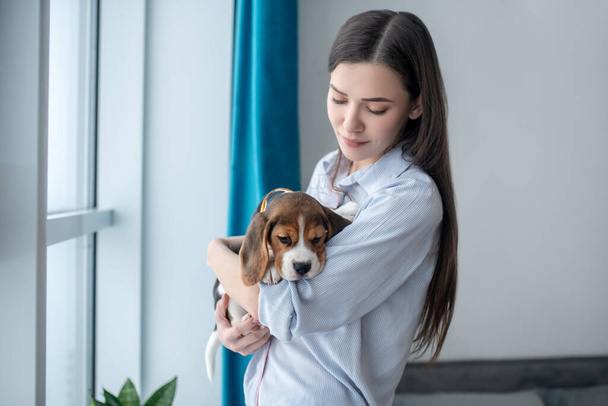 Dark-haired girl with her puppy at home feeling peaceful - Fotografie, Obrázek