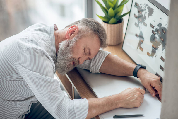 Egy férfi a munkahelyen alszik, fáradtnak érzi magát. - Fotó, kép
