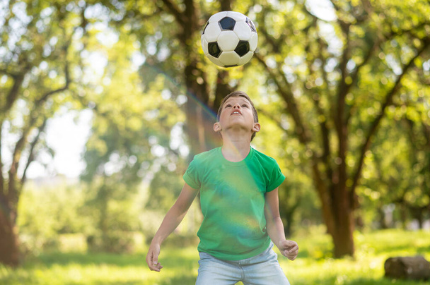 Attentive boy looking at soccer ball up in air - Foto, afbeelding