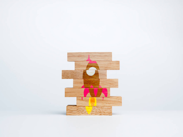 Business startup concept. Wood stack with the jigsaw puzzle with incomplete rocket symbol on white background. Learning for success. - Photo, Image