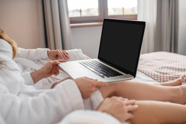 Female hands holding open laptop on bed - Foto, afbeelding