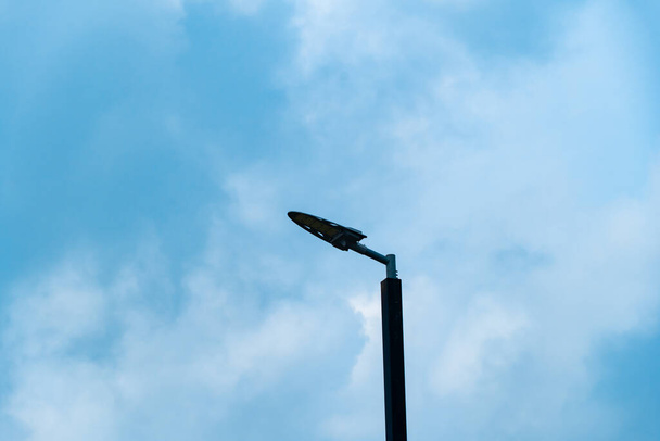 силуэт уличного освещения, фонарь пост с белым облаком и голубым небом фон - Фото, изображение