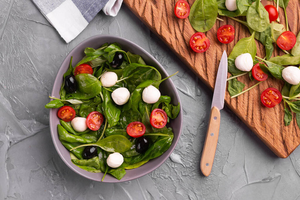 Fresh salad with mozzarella cheese, tomato and spinach. Healthy dieting food, top view. - 写真・画像
