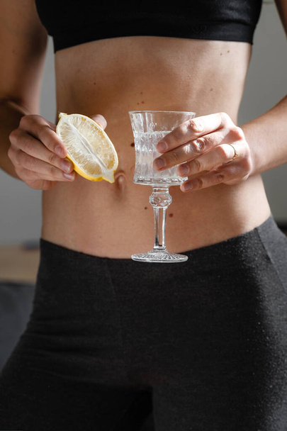 Close up of young fit slim woman preparing water with lemon juice. Morning ritual. Healthy antioxidant. Slimming diet. Boost immunity and metabolism  - Foto, Imagen