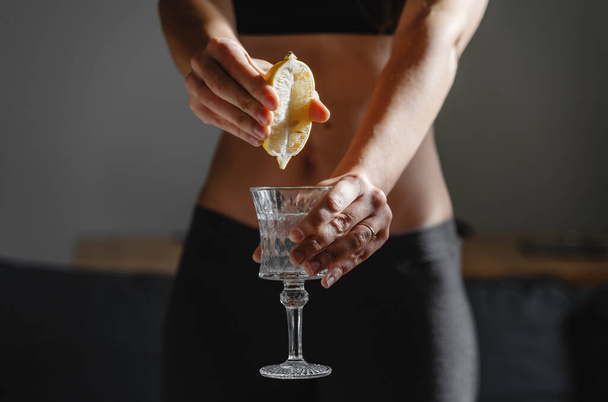 Close up of young fit slim woman preparing water with lemon juice. Morning ritual. Healthy antioxidant. Slimming diet. Boost immunity and metabolism  - Фото, зображення