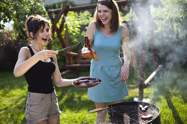 Tytöt tekevät ruokaa grillillä
 - Valokuva, kuva