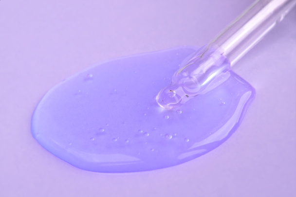紫色の背景に液体ヒアルロン酸を持つピペット。化粧品とヘルスケアの概念を閉じる - 写真・画像