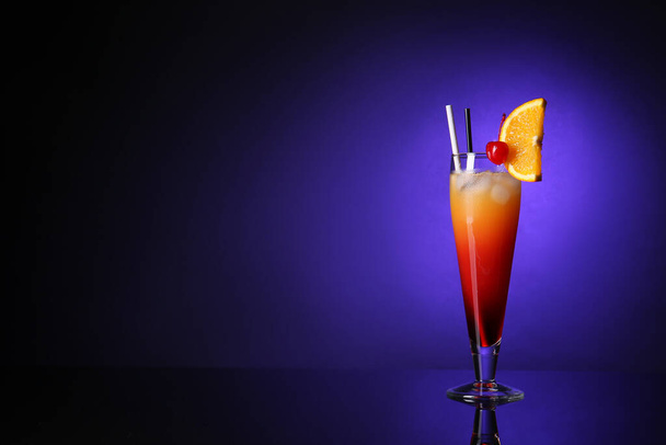 Glass of tasty Tequila Sunrise cocktail on dark color background - Fotoğraf, Görsel