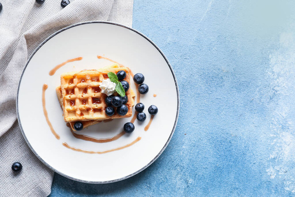 Plate of tasty Belgian Waffles with blueberry on blue background - Photo, Image