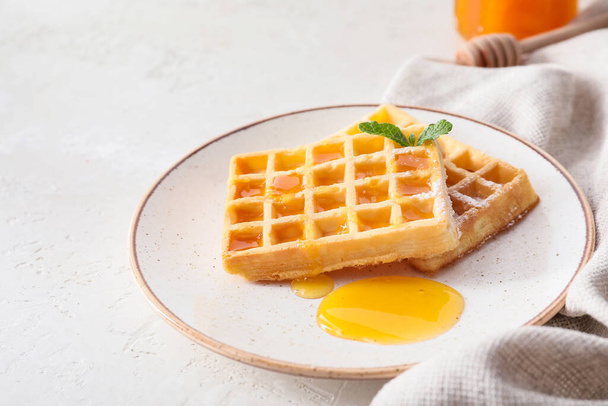 Тарелка вкусных бельгийских вафель с медом на белом фоне - Фото, изображение