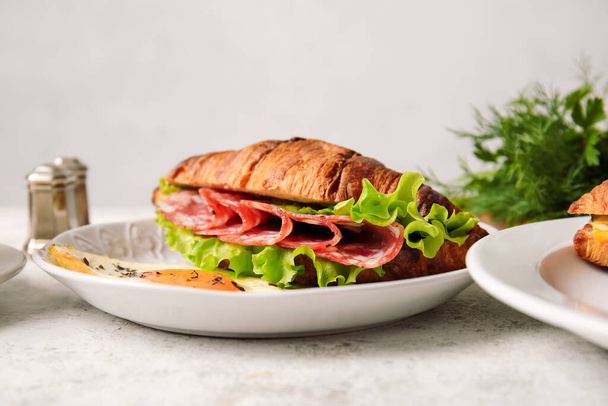 Тарелка с вкусным бутербродом с круассаном на светлом фоне - Фото, изображение
