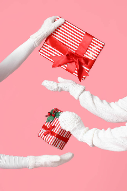 Women exchanging Christmas gifts on pink background - 写真・画像