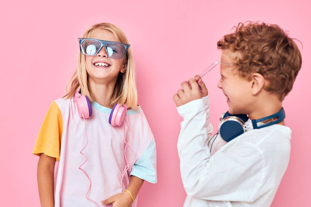 divertido niño y niña en gafas de sol divertirse con los amigos de color rosa fondo - Foto, imagen