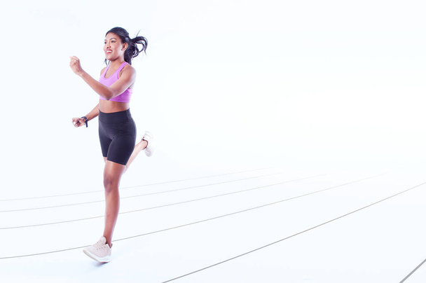 A young happy running female in a sports outfit against a white background - Φωτογραφία, εικόνα